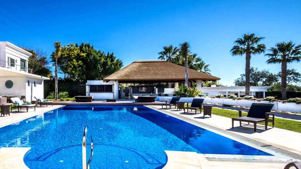 Poolside thatched outdoor living space with kitchen facilities