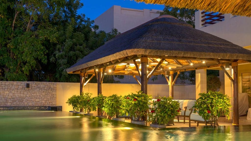 Thatched outdoor entertainment pool cabana with BBQ firepit