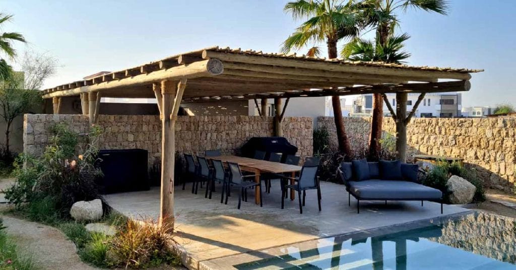 A wooden pergola by the poolside in Dubai, constructed with Cape Reed that offers shade and elegance.