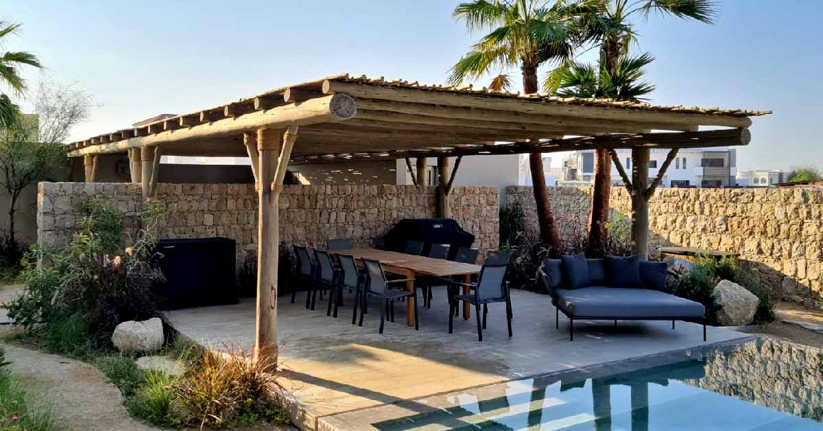 A wooden pergola by the poolside in Dubai, constructed with Cape Reed that offers shade and elegance.