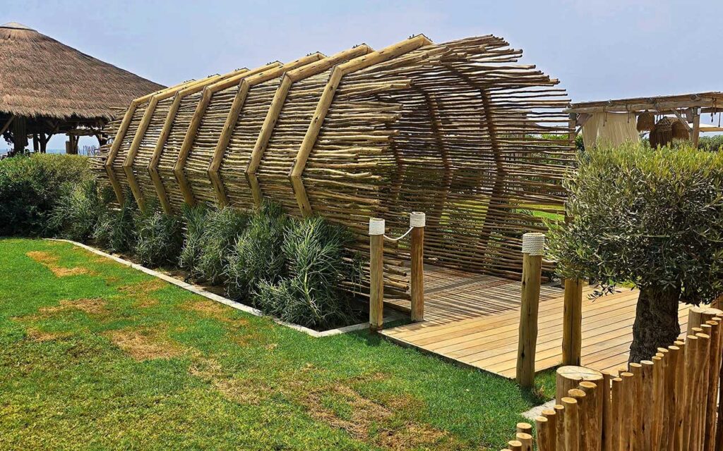 Curved timber lath entrance structure leading to a beachfront deck at Lumi Beach