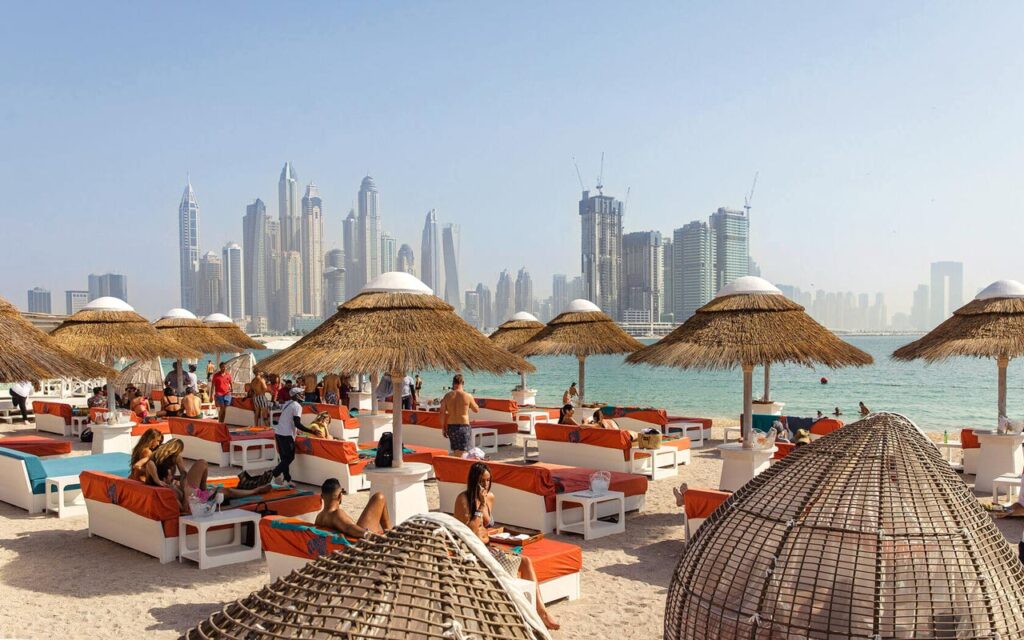 Lucky Fish beach club with Cape Reed thatched umbrellas and white cement capping, Dubai skyline in the background