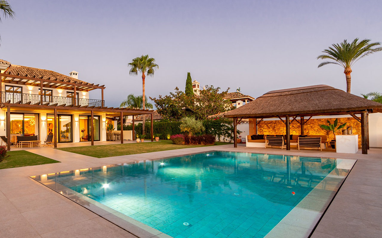 Villa en Marbella con piscina y gazebo de junco africano de Cape Reed iluminado al atardecer